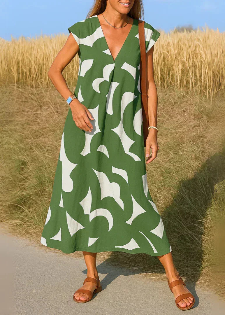 Femme portant une robe longue verte à motifs abstraits blancs, sandales d'été, champ en arrière-plan