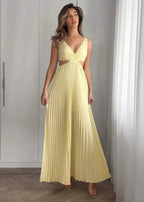 Femme portant une robe longue plissée jaune pâle à décolleté et découpes, debout en intérieur