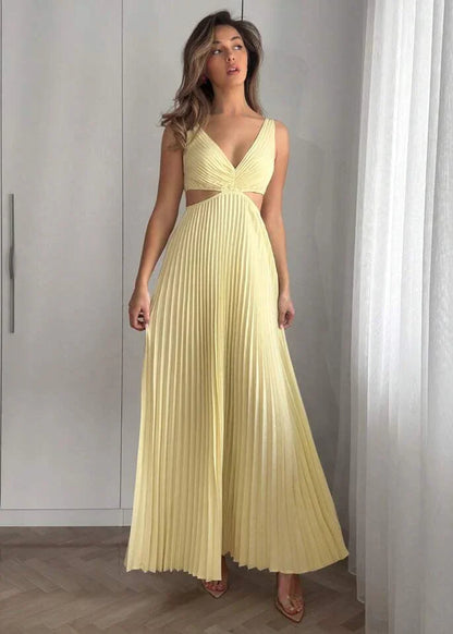 Femme portant une robe longue plissée jaune pâle à décolleté et découpes, debout en intérieur
