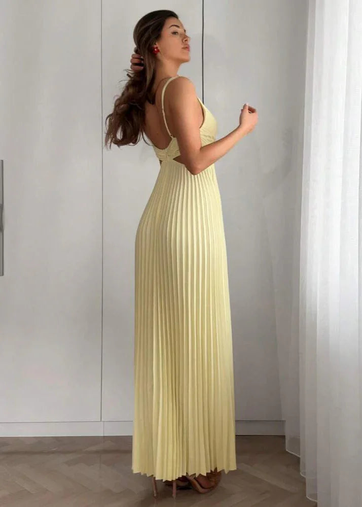 Femme portant une robe longue plissée jaune pâle, élégante dans un intérieur lumineux