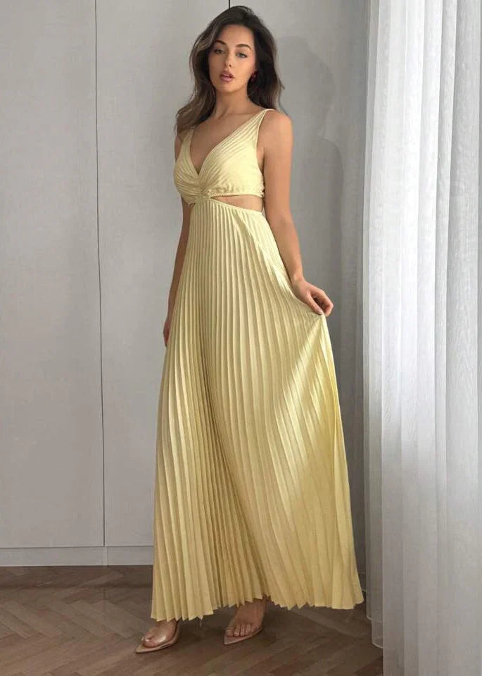Femme portant une robe longue plissée jaune pâle à décolleté croisé, mode élégante, intérieur lumineux