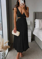 Femme portant une robe noire plissée sans manches, coupe midi, tenant une pochette blanche élégante.
