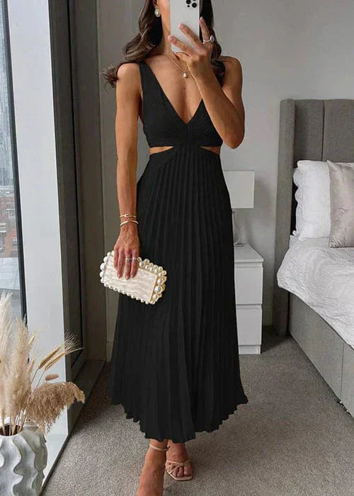 Femme portant une robe noire plissée sans manches, coupe midi, tenant une pochette blanche élégante.