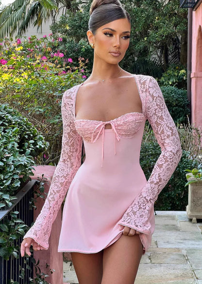 Femme portant une robe rose en dentelle à manches longues en extérieur, style élégant