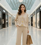 Femme élégante en ensemble beige à boutons dorés, tenant des sacs shopping dans un centre commercial
