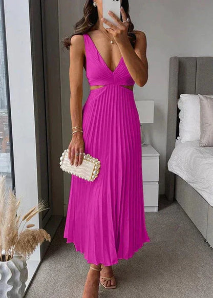 Femme portant une robe longue plissée fuchsia à décolleté plongeant, tenant une pochette perles élégante.