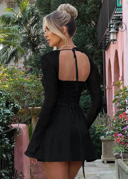Femme de dos portant une robe noire à manches longues en dentelle, dos nu, en jardin fleuri.