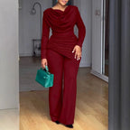 Femme portant un ensemble élégant bordeaux manches longues, pantalon large, sac à main vert
