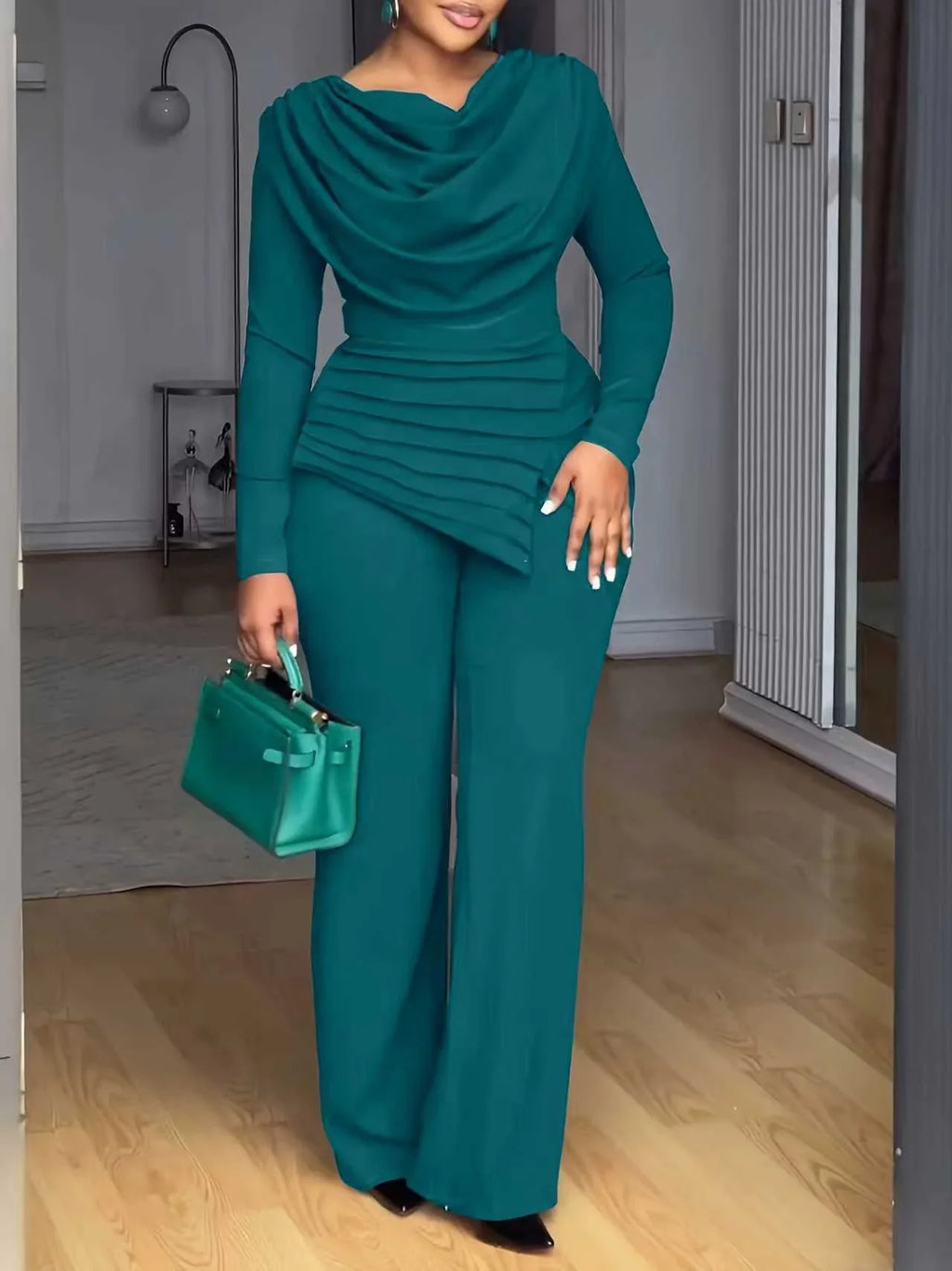 Femme portant un ensemble élégant vert, pantalon large et haut drapé, sac assorti, mode chic.