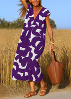 Femme en robe longue violette à motif graphique, sandales et sac marron, champ de blé