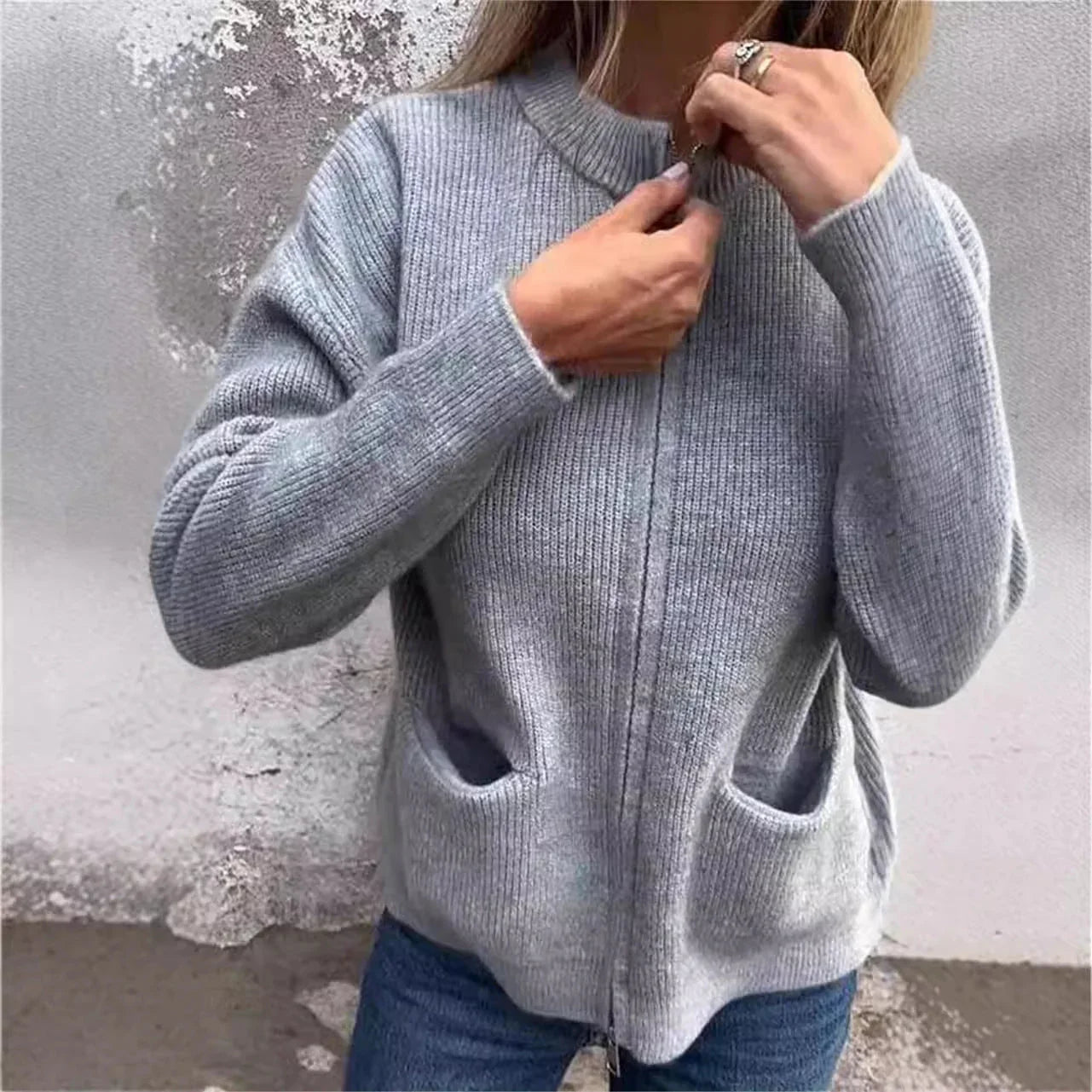 Femme portant un cardigan gris zippé en maille, poches avant, tenue décontractée.
