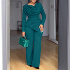 Femme portant un ensemble pantalon vert élégant avec sac à main assorti, mode chic intérieure