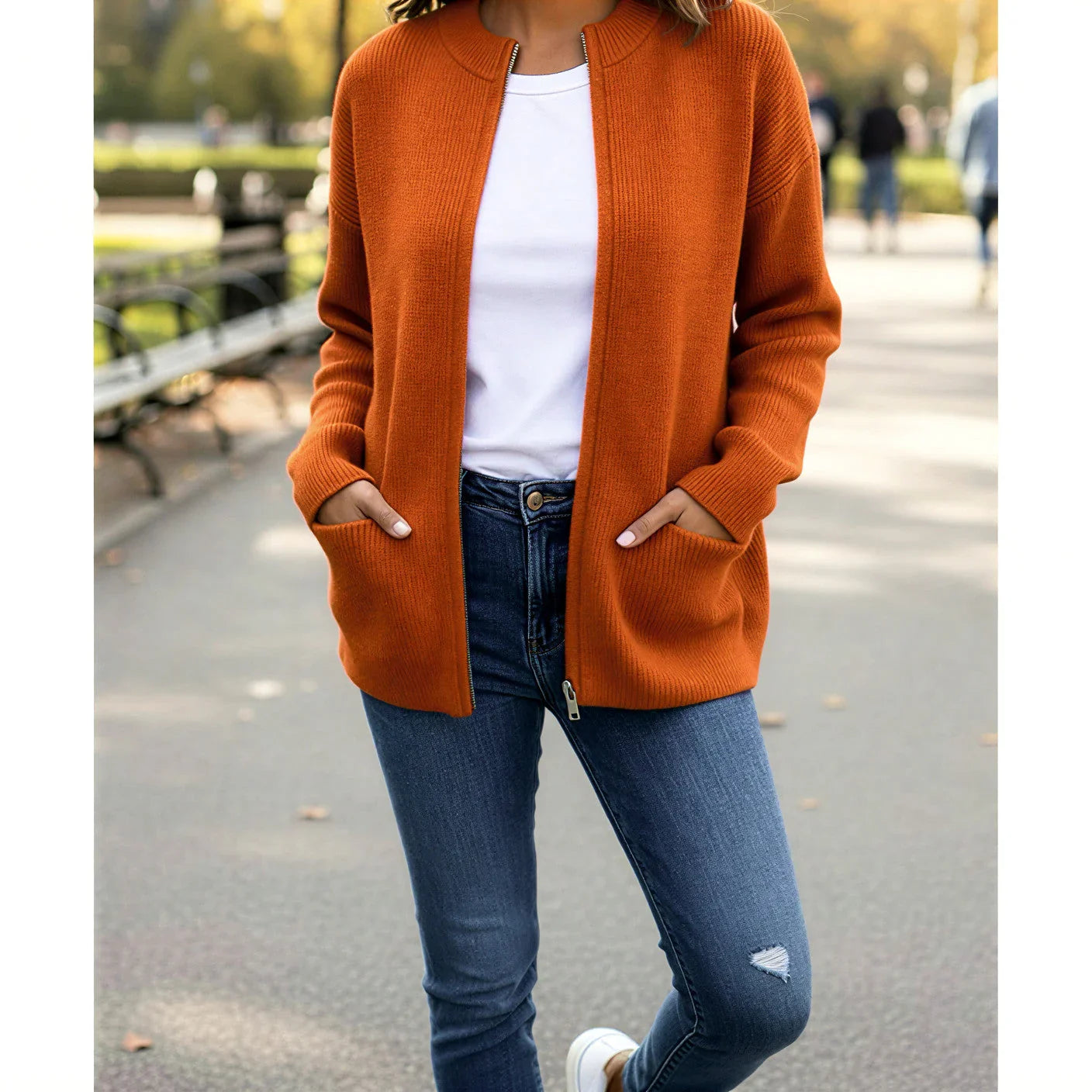 Femme portant un cardigan orange en maille, t-shirt blanc et jean bleu, mode automne