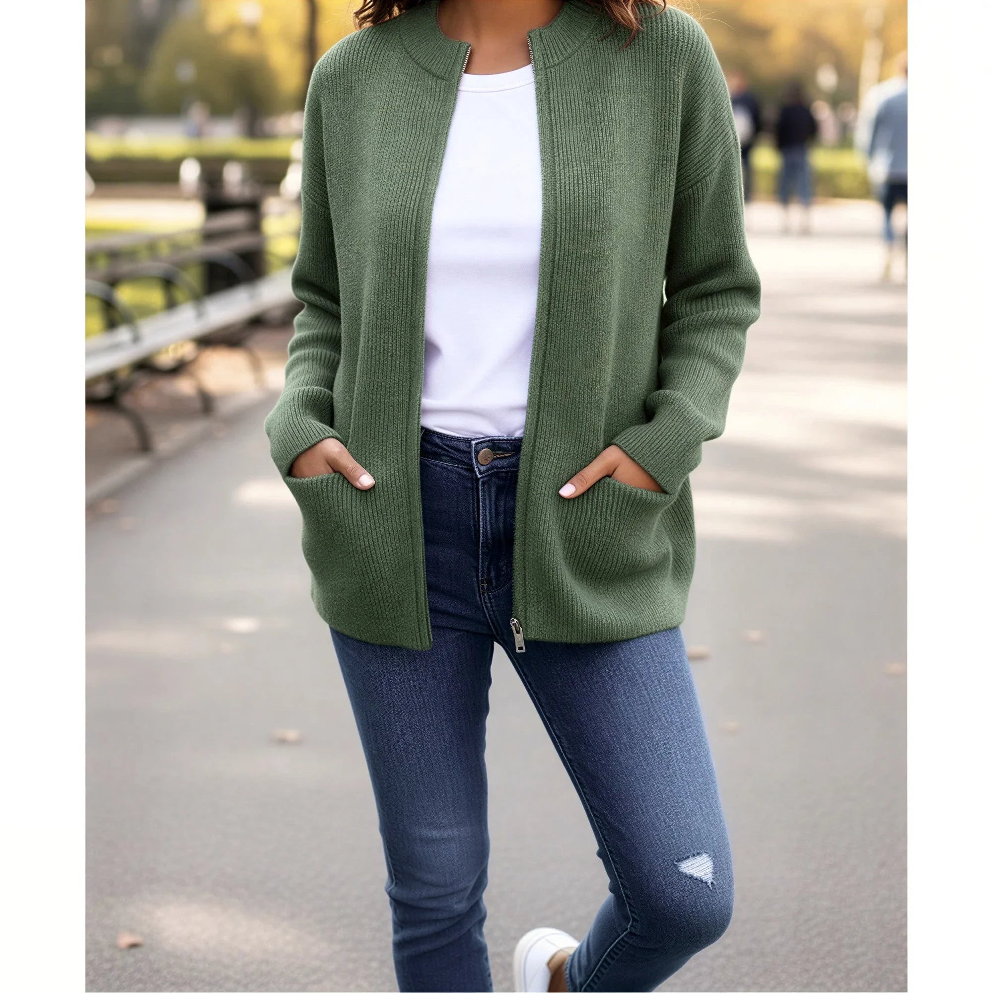 Femme portant un gilet vert en maille avec poches, t-shirt blanc et jean, promenade en parc
