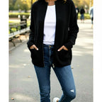 Femme avec gilet noir, t-shirt blanc et jean bleu tendance en extérieur urbain
