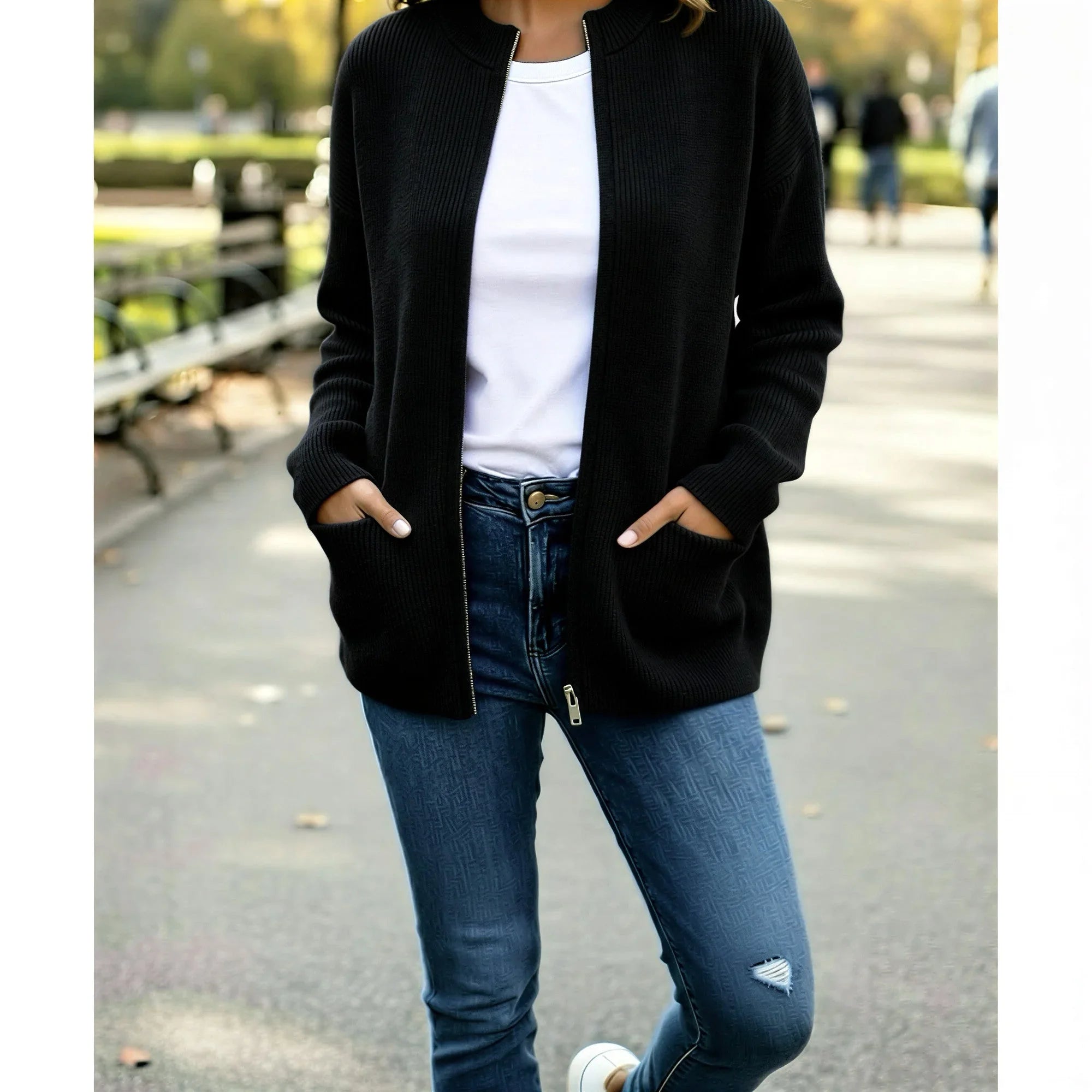 Femme avec gilet noir, t-shirt blanc et jean bleu tendance en extérieur urbain