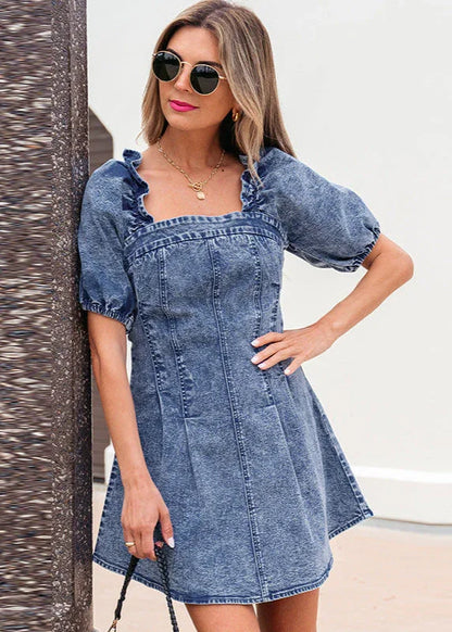 Femme portant une robe courte en jean bleu à manches bouffantes et col volanté, look élégant.