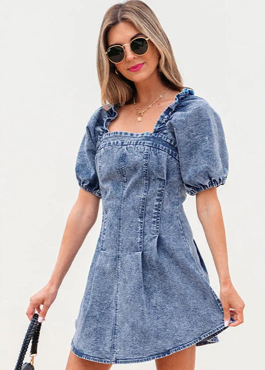 Femme portant une robe en jean bleu à manches bouffantes et col carré, look estival tendance