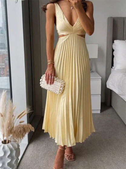 Robe longue plissée jaune pastel sans manches, décolleté, portée avec pochette perles, élégante.